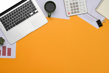 Top view laptop, financial reports, calculator and notepad on yellow background