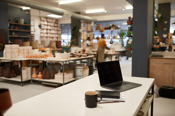 Laptop sitting on a table in a large ceramics manufacturing studio