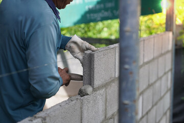 masonry worker make concrete wall by cement block and plaster at construction site