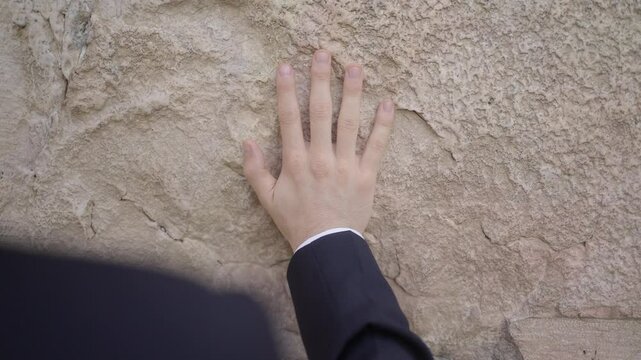 Othodox jewish man leyning with hand on western wall