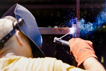 Welding Works. Welder Men Welds Metal Frame with Welding Rods on Dark Background. Welding Sparks...