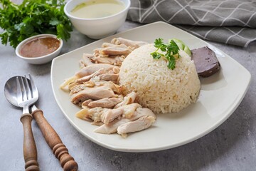 Chicken and rice with coriander and cucumber with sauce and soup in a white plate, hainanese chicken rice, thai called khao man gai, asian food, thai food