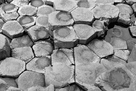 Black and white close-up of the basalt columns at Giant Causeway, shot from above. The hexagonal shapes and textures of the stones create a natural pattern