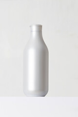 Abstract dispenser bottle in silver color on white podium. Cosmetic liquid product like gel or shampoo conditioner at grey background.