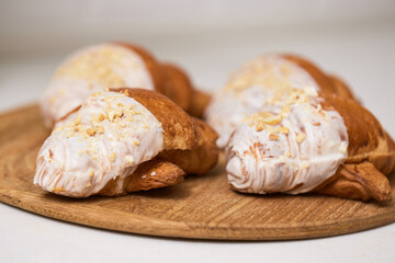 Delicious fresh croissants on wooden tray on white table, closeup