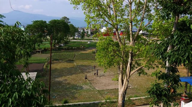 Children playing football or soccer in a small ground surrounded by nature.