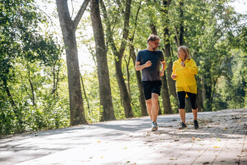 Obraz premium Front view, jogging, sports. Senior couple together outdoors at nature