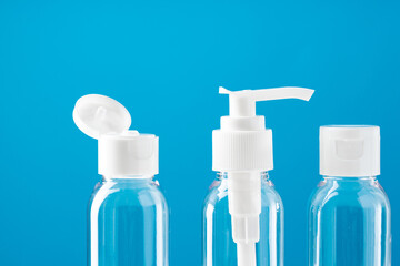 Clear plastic bottles with pumps arranged on a table against a bright blue background