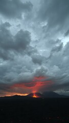 Fototapeta premium A dramatic sky filled with dark clouds of volcanic ash, with fiery orange tones visible near the horizon as lava flows in the distance 