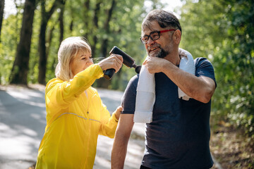 Woman is making massage for the man. Senior couple together outdoors at nature