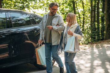 Car is parked, walking. Senior couple together outdoors at nature