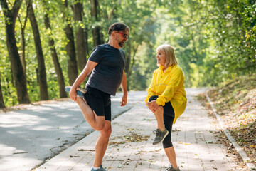 On the sidewalk. Doing fitness exercises. Senior couple together outdoors at nature