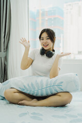 Image of Asian girl listening to music and relaxing in bed