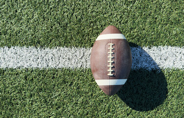 Close up of an american football on the field, players in the background