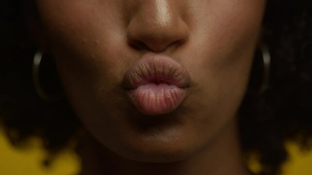 Close-up of lips puckering for a kiss on yellow background