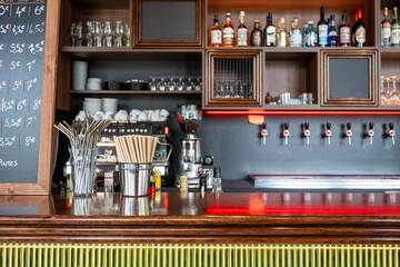 Comptoir d'un bar avec machine à café, tireuse à bière et rangements de verres et boissons