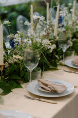 Modern stylish wedding table setting. The wedding decor. The pastel colors flowers bouquet. Natural beautiful wedding decorations. Minimalistic wedding decorations