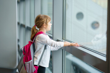 Little Girl at the Airport Waiting for Boarding at the Big Window. Cute Kid Stands at the Window against the Backdrop of Airplanes. Looking Forward to Leaving for a Family Summer Vacation