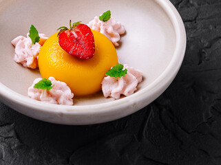 Delicious mango panna cotta dessert with strawberry and mint on black background