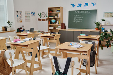 No people wide shot of modern school classroom interior equipped with wooden furniture and decorated with posters on career guidance day