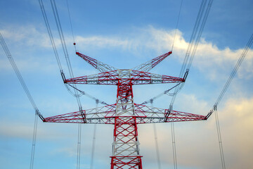 High voltage pole with electric wires against the background of evening cloudy sky.