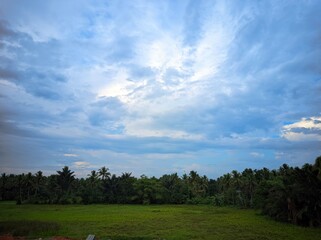 Fototapeta premium The photo depicts a beautiful landscape with a dramatic sky. The sky is divided into two distinct parts: one side is filled with dark, stormy clouds, while the other side is a clear, bright blue.