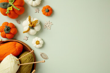 Top view handcrafted crochet pumpkins, autumn decor, and yarn on pastel green background.