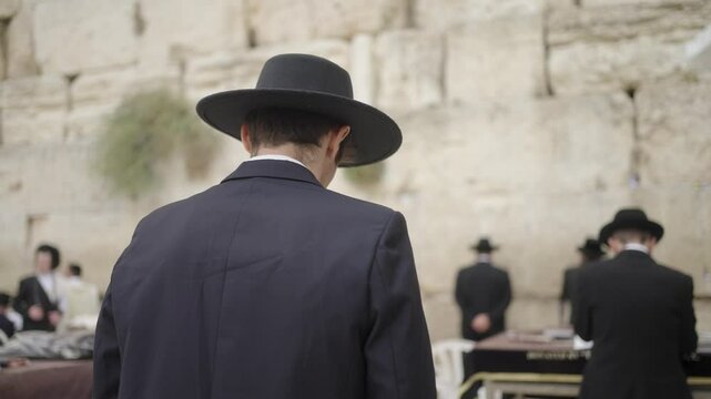 Religious Orthodox Jewish Men Praying With Torah At Western Wall In Jerusalem, Israel. medium shot, rear view
