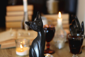 Books, lit candles, red wine, snacks and various deocration on the table. Dark academia or Halloween concept. Selective focus.