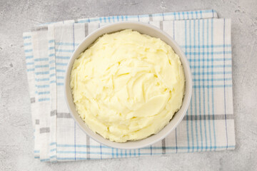 Mashed potatoes in white bowl on grey concrete background. Healthy food