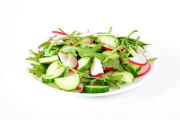 a plate of vegetables with radish and cucumber slices covered with arugula