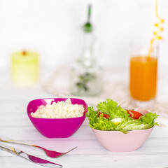 bowls of snacks and cookies on wooden white table. Rice, salads, juice, crackers.