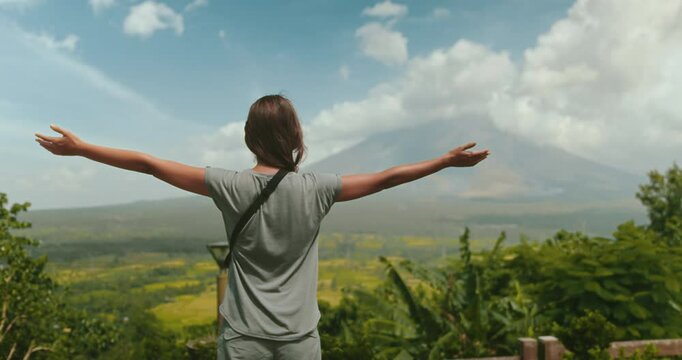 Young woman is embracing the breathtaking beauty of a tropical landscape, with the majestic mayon volcano standing tall in the distance
