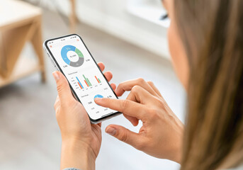 Close-up of woman analyzing business data on smartphone with interactive charts