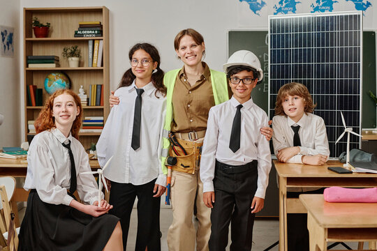 Group of gen alpha students and female engineer posing for portrait in classroom on vocational guidance day at school