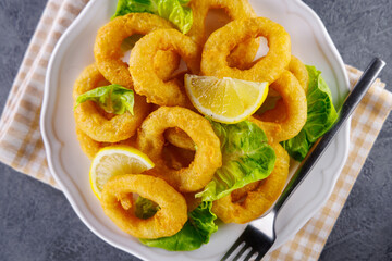 Fried calamari rings with lettuce and lemon. Ideal for seafood appetizers and gourmet dining...