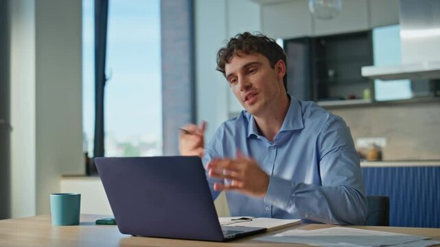 Smiling man talking virtual meeting discussing projects at home kitchen closeup.