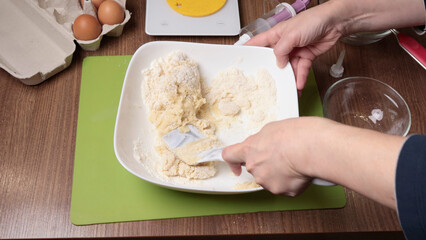 Process of making dough. Woman mixed powdered sugar, almond flour and egg white with silicone spatula in bowl. Baking macarons at home. Hands close-up.