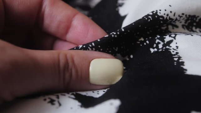Hand touching, examining polyester fabric, quality and tactile properties for sewing.
