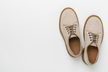 Beige suede shoes on color background, top view