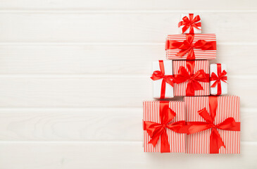 Gift boxes in Christmas tree shape on wooden background, top view