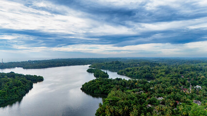 Obraz premium Aerial view of a calm Sri Lankan river. Experience the tranquil beauty of a winding river surrounded by vibrant greenery under a dramatic sky in Sri Lanka.