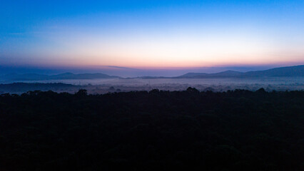 Sunrise over misty hills in Sri Lanka’s landscape. The sun rises slowly, casting a soft glow over mist-covered hills and valleys in the serene landscape of Sri Lanka.