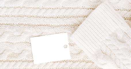 Fototapeta premium Background of top view of textile fabric of woven cozy soft casual sweater of white colour with geometric pattern knitted from warm wool or merino yarn with price tag or label with sale discount