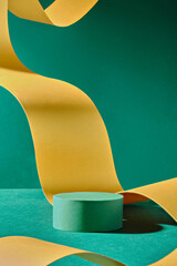 A close-up photo of a green podium that is cylindrical and has an elegantly curled yellow paper...