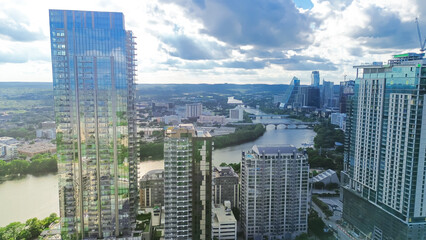 Obraz premium Aerial view Austin Downtown skyscrapers along lush green curved Colorado River, high rise office buildings under construction, fast growing Texas Capital City, modern skyline hotel condos