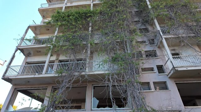Abandoned building overtaken by nature in Varosha with broken windows and vines climbing the facade