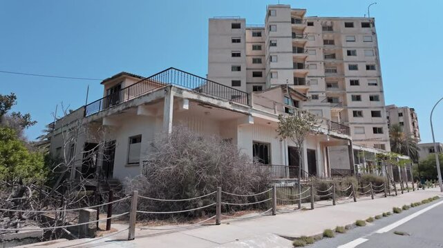 Abandoned building under bright blue sky surrounded by trees in Varosha, Europe&rsquo;s largest ghost town