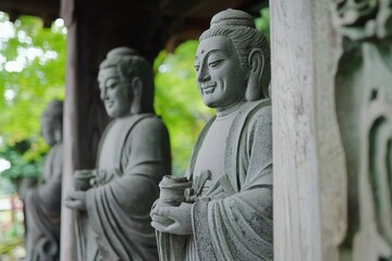 Obraz premium Serene stone statues of Buddhas surrounded by lush greenery in a tranquil garden setting