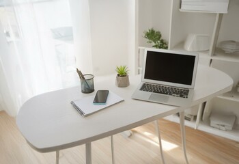 A white table with a laptop, notepad, and smartphone.